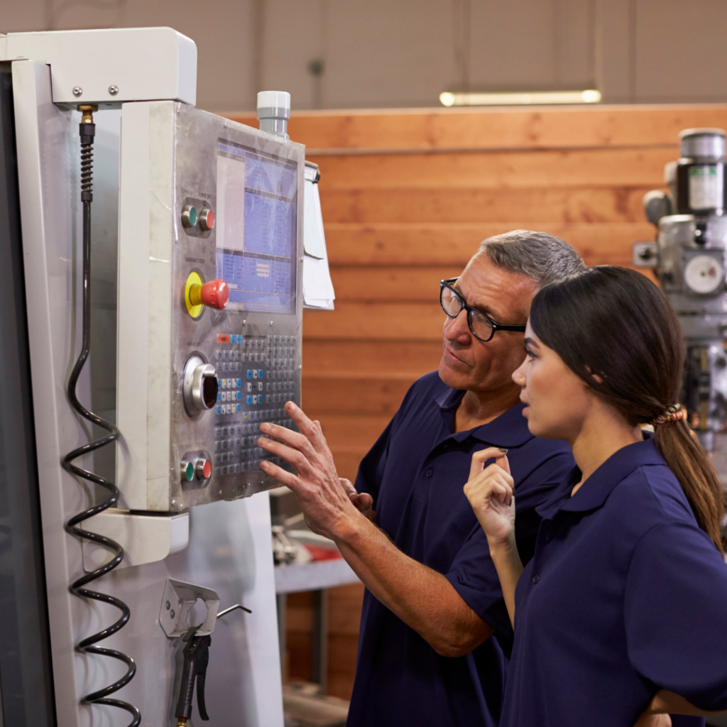 A man showing a young woman how to operate machinery