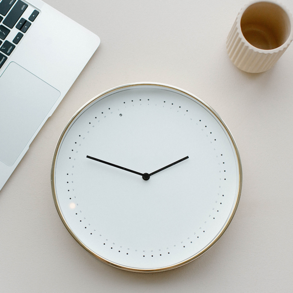 Photo of a clock with a laptop and cup